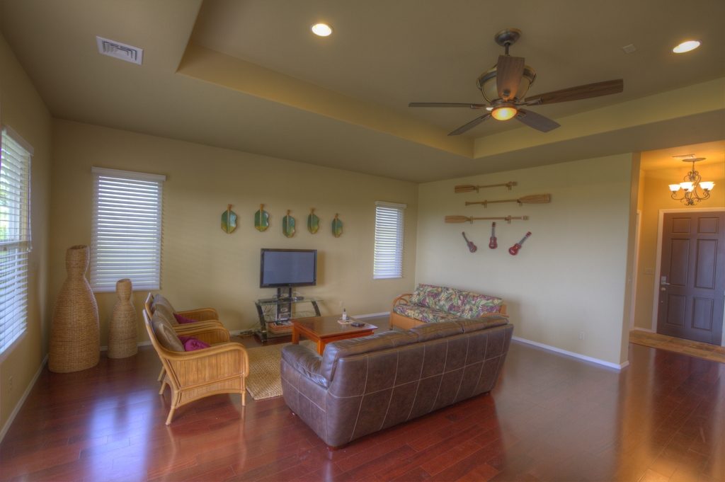 Warm living room with leather sofas, a ceiling fan and polished wood floors